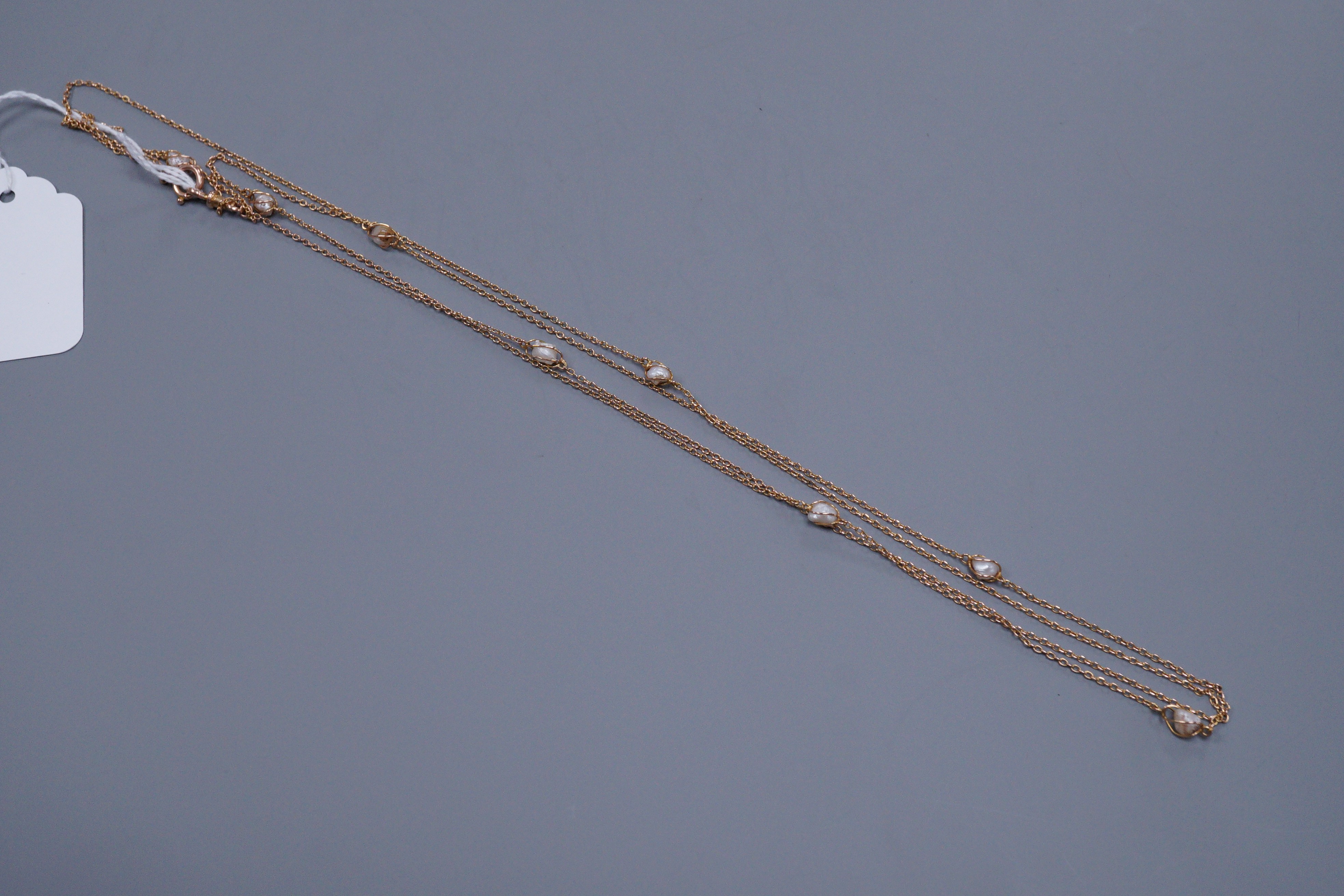 An early 20th century unmarked gold and baroque pearl chain necklace, 137cm
